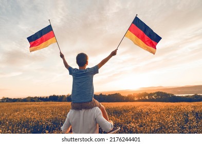 A Patriotic Father And Child Waving Germany Flag On Sunset