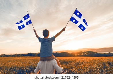 A Patriotic father and child waving Quebec flags on sunset