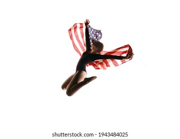 A patriotic female dancer is seen in front
of a white background. She proudly waves the 
American flag around her in a cheerful manner. - Powered by Shutterstock