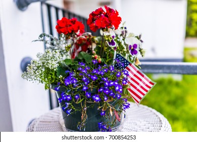 Patriotic flower pot with American flags and red and blue flowers on porch