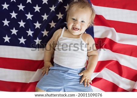 Patriotic holiday. Cute caucasian baby ten-eleven months old with blonde hair and blue eyes with American flag at home. USA celebrate independence day 4th of July. High quality photo