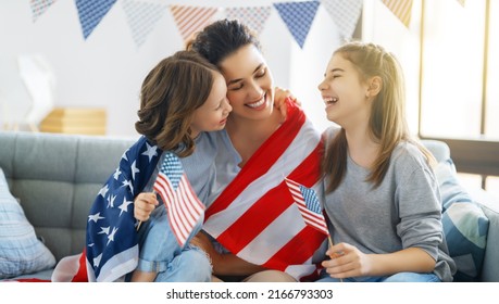 Patriotic holiday. Happy family, mom and daughters children girls with American flag at home. The USA celebrate 4th of July.