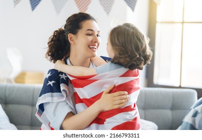 Patriotic Holiday. Happy Family, Mom And Daughter Child Girl With American Flag At Home. The USA Celebrate 4th Of July.