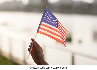 Patriotic holiday. Happy family, mother and daughter with American flag outdoors on sunset. USA celebrate independence day 4th of July.