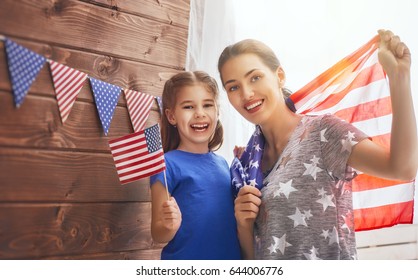 Patriotic holiday. Happy family, mother and her daughter child girl with American flag at home. USA celebrate 4th of July.