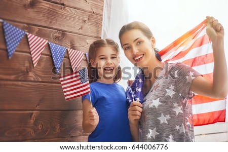 Patriotic holiday. Happy family, mother and her daughter child girl with American flag at home. USA celebrate 4th of July.