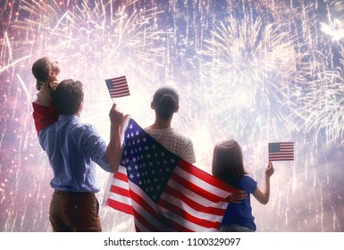 Patriotic Holiday. Happy Family, Parents And Daughter Child Girl With American Flag Outdoors. USA Celebrate 4th Of July.