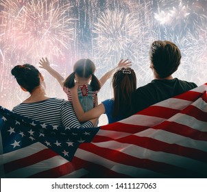 Patriotic holiday. Happy family, parents and daughter child girl with American flag outdoors. USA celebrate 4th of July.