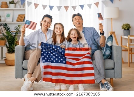 Patriotic holiday. Happy family, parents and daughters children girls with American flag at home. The USA celebrate 4th of July.