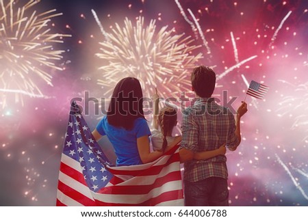 Patriotic holiday. Happy family, parents and daughter child girl with American flag outdoors. USA celebrate 4th of July.