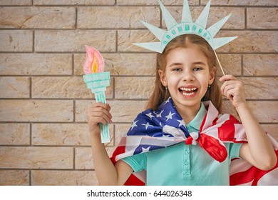 Patriotic holiday. Happy kid, cute little child girl with American flag in the room indoors. USA celebrate 4th of July.