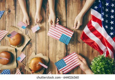 Patriotic Holiday. Mother, Father And Child Are Doing Burgers. Happy Family Are Celebrate 4th Of July. Top View With American Flag In The Room At Home.