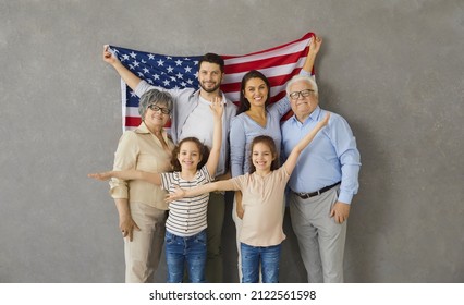 Patriotic holiday. Portrait of happy three generations family with american flag on gray background. Older grandparents with their children and two granddaughters twins smile looking at the camera. - Powered by Shutterstock