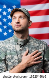 patriotic military man pledging allegiance near american flag on blurred background