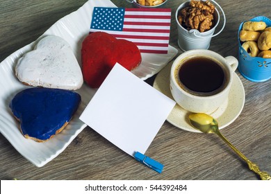 Patriotic party Concept -  Heart shaped cookies color red, blue, white. Cup of coffee (tea), USA flag, decoration on old wooden table. toned filter image. space for text - Powered by Shutterstock