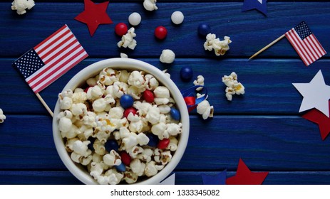 Patriotic popcorn on July 4 in a white bucket with the American flag on a blue wooden background.The US independence day. - Powered by Shutterstock