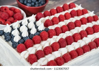 Patriotic, red white and blue, American flag cake. Fresh blueberries and raspberries in the background. Concept for Fourth of July celebration. - Powered by Shutterstock