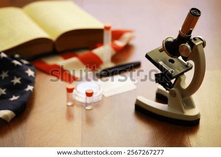 Patriotic Science: Microscope with American Flag and Open Book in Background for Educational and Research Themes