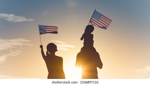 Patriotic silhouette of family waving American USA flags. 