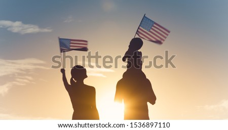 Patriotic silhouette of family waving American USA flags. 