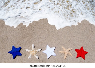 Patriotic USA Background With Starfishes And Blue, White And Red Stars On The Sandy Beach - Holiday Concept