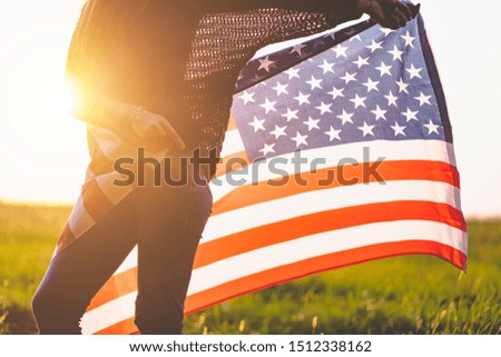 Patriotic woman with american flag outdoors at sunset. Travel to america and celebrate holiday of 4th of july in usa 