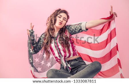 Patriotic young beautiful girl with the flag of America on a colored background, concept of patriotism and national holiday