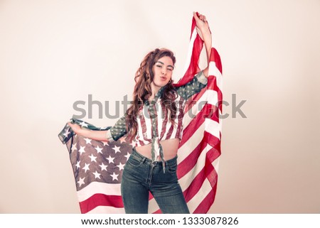 Patriotic young beautiful girl with the flag of America on a colored background, concept of patriotism and national holiday