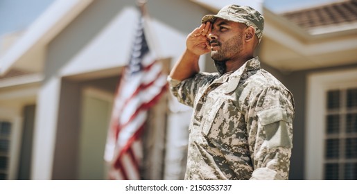 Patriotic young soldier saluting while standing outside his home. Member of the United States Marine Corps showing honour and respect on Veterans Day. - Shutterstock ID 2150353737