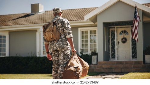 Patriotic young soldier walking towards his house with his luggage. Rearview of an American serviceman coming back home after serving in the military. - Powered by Shutterstock