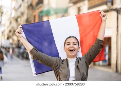 Patriotic young woman waving the flag of France on the city street - Powered by Shutterstock