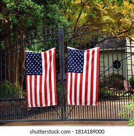 Patriotism is shown by home owner with two American flags hanging on their black wrought iron gate.  