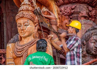  Pattaya Chonburi Thailand December 17 2017. Asian men carving wooden statues outside a Buddhist temple in Pattaya Thailand. Yellow hard hat on Thai wooden carver at a famous temple outside Pattaya.