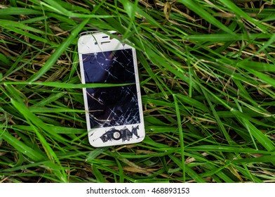 Pattaya, Thailand - August 15, 2016 Photo of a broken iPhone 4s in green grass. iPhone 4s is a smartphone developed by Apple Inc.