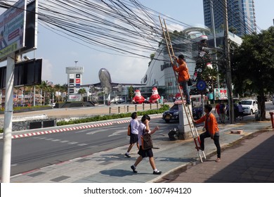 Pattaya, Thailand - December 23, 2019: Workers. Man on a bamboo ladder leans against the power line. Other man holds ladder.