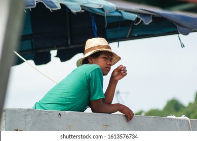 Pattaya, Thailand - June 21, 2012. Thai Young Guy Working In A Green T-shirt And A Straw Hat On The Pier.