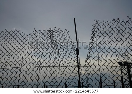 pattern or background of net over blue sky. silhouette of a ripped metallic net.  wire fence made of thin wire against heaven. 