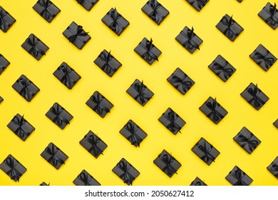 Pattern with black gift boxes with black ribbons on bright rich yellow background. Black Friday sale flat lay, top view. Discount, advertising and sale concept. Creative minimalist design