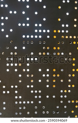 Pattern of black and white dots on a wall. The dots are arranged in a grid, with some larger and some smaller. The overall effect is a somewhat abstract and modern look