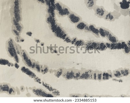 The pattern of black-gray spots on white fabric, closeup as a texture for background. Fragment of an absract monochrome ornament printed on lightweight textile. Details of hipster or ethnic motifs.