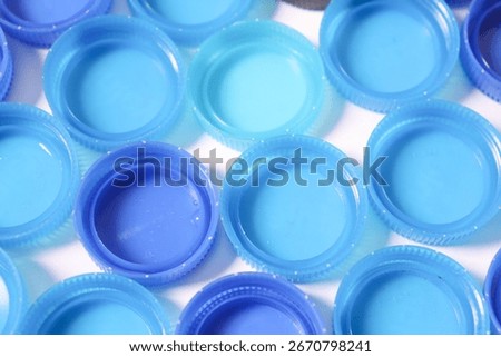 A pattern of blue plastic bottle caps, ideal for recycling concepts. The image is clean and bright, highlighting the texture and color of the caps in detail.