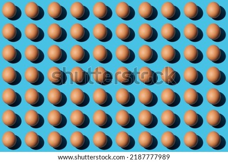 Pattern of brown chicken eggs isolated on blue background. Happy Easter day. Close-up, top view.