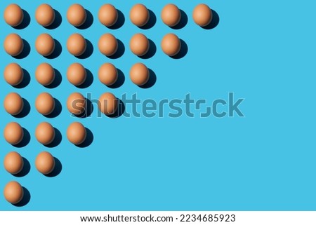A pattern of brown chicken eggs lying diagonally on the upper left half of the blue background. Right side for copy space,  top view.















 

 





































 







