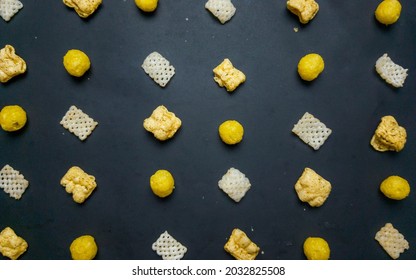 Pattern Of Cheese Puffs And Chip And Crackers On Black Background Viewed From Top