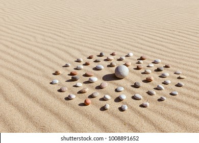 Pattern of colored pebbles in the shape of a circle on clean sand. The concept of serenity and meditation