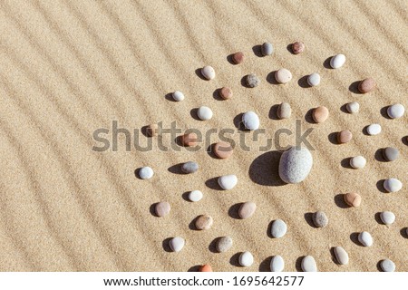 Pattern of colored pebbles in the shape of a circle on clean sand. The concept of serenity and meditation. Flat lay, Top view