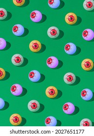 Pattern of colorful bloody eyeball Halloween candies on a vivid green background. Spooky concept.
