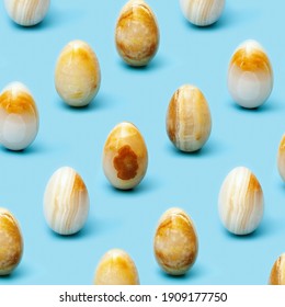 Pattern from Easter eggs made from Natural gemstone onyx on blue background. Trendy spring holiday arrangement. 
