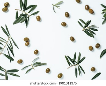 Pattern with green olives and olives tree leaves and branches on white background, copy space in center. Olive tree fruits and branches, top view or flat lay. Stock Photo