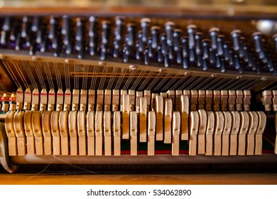 Pattern of hammers and strings inside piano, close up. One hummer in action while key is pressed. Stand out from the crowd concept.